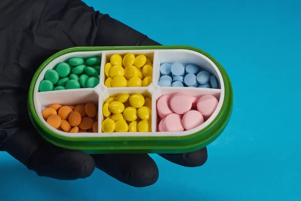 A hand using a pill splitter on a small chewable tablet